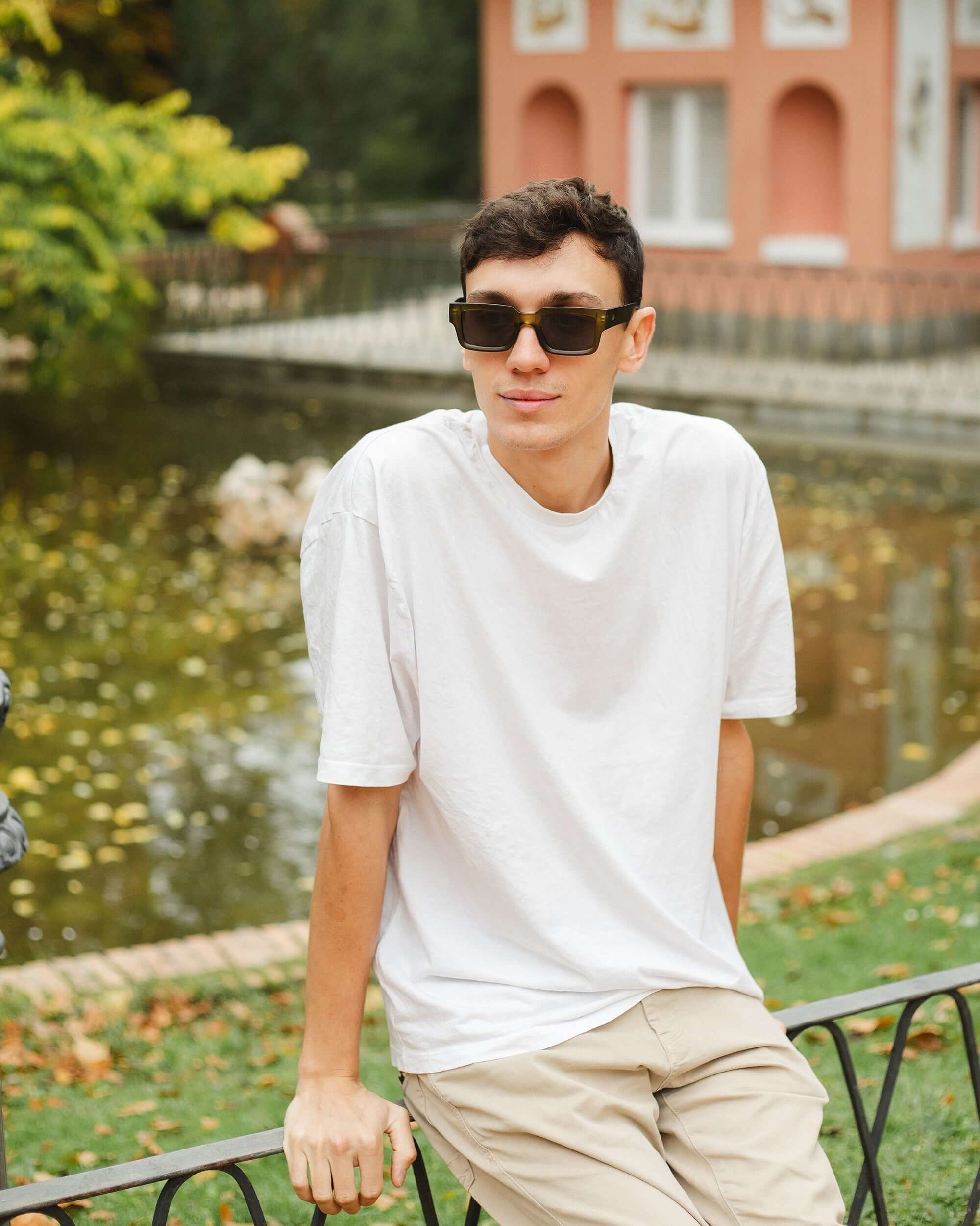 Joven con gafas de sol Hanukeii® Islander Green / Black junto a un estanque en un día soleado.